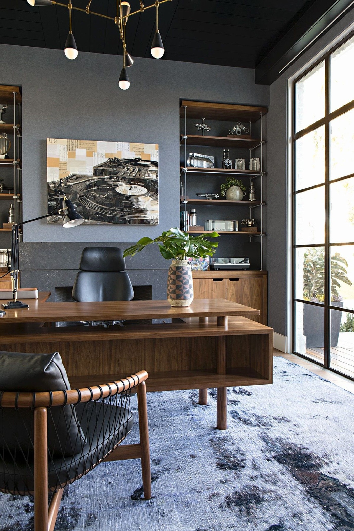 Home office with large brown wood table and a reccord player framed photo on wall behind it