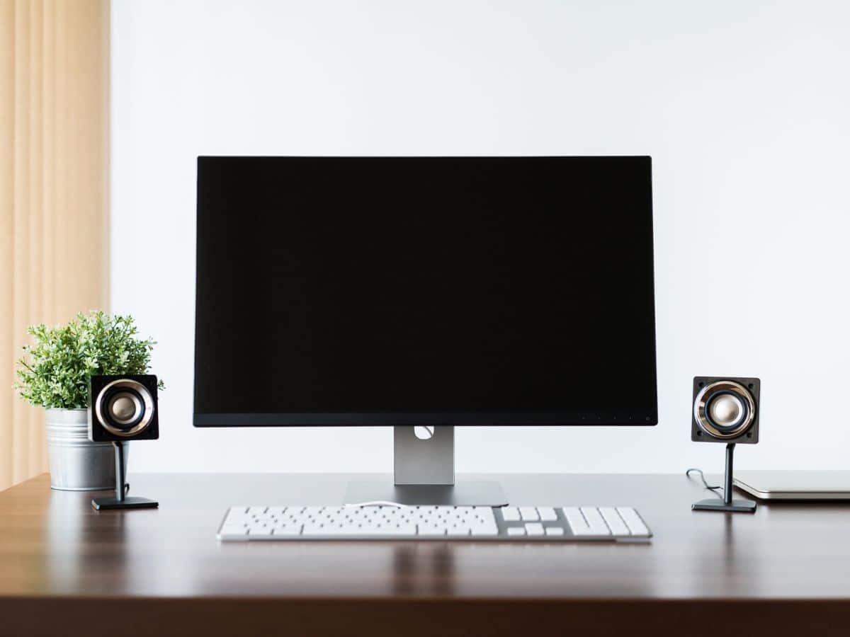 A desk with screen, keyboard and speakers on either sides