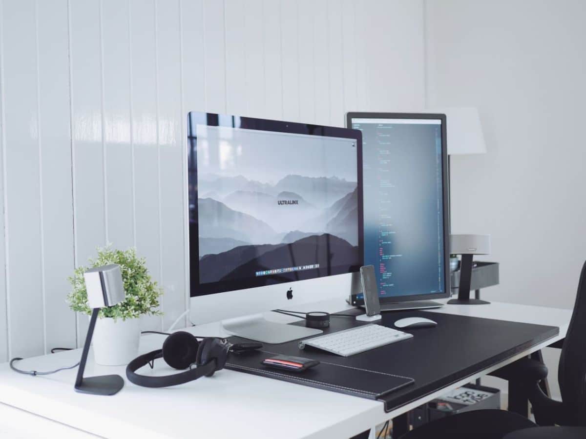 Apple desktop computer on a desk with white wall behind it