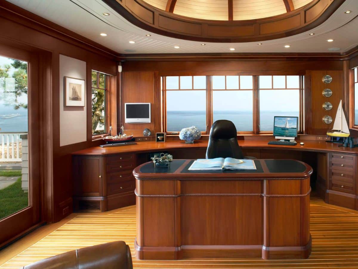 Large home office with wood table in middle and curved wood cabinets along the wall behind it