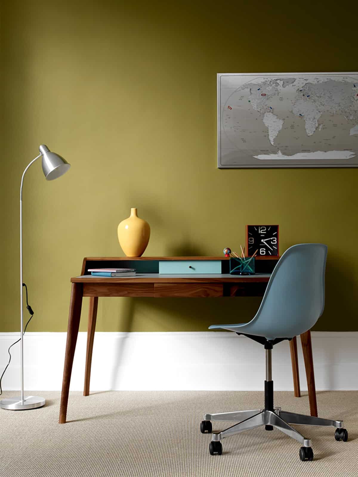 Office table along an olive wall with a map of world hanging on it