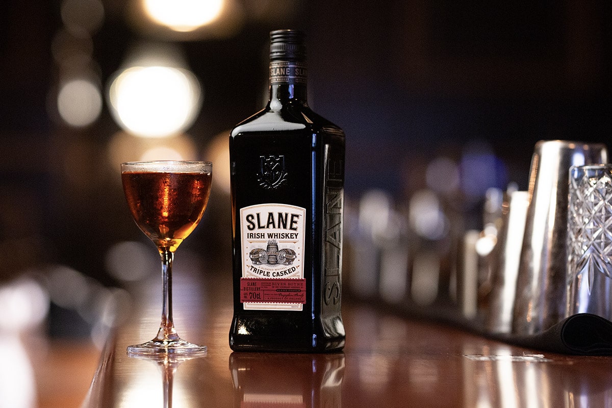 Bottle of Slane Irish whiskey next to a filled glass