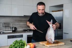 Chef Rantissi holding a knife with a fish in the other hand