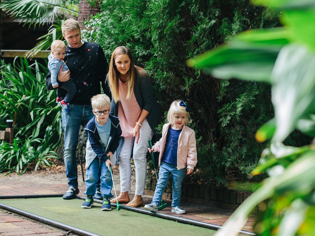 family with kids playing mini golf