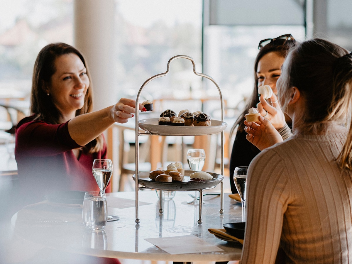 group of three young women smiling and eating dessert at the reveley