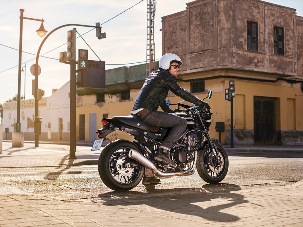 man riding black kawasaki z900rs cafe on the street