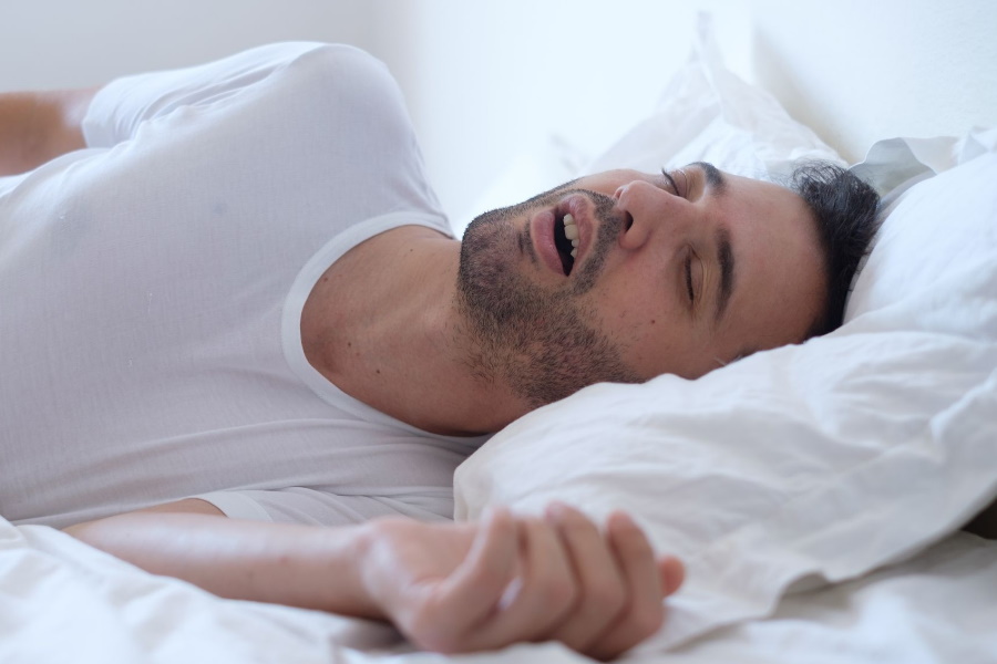 A man sleeping in bed with his mouth open