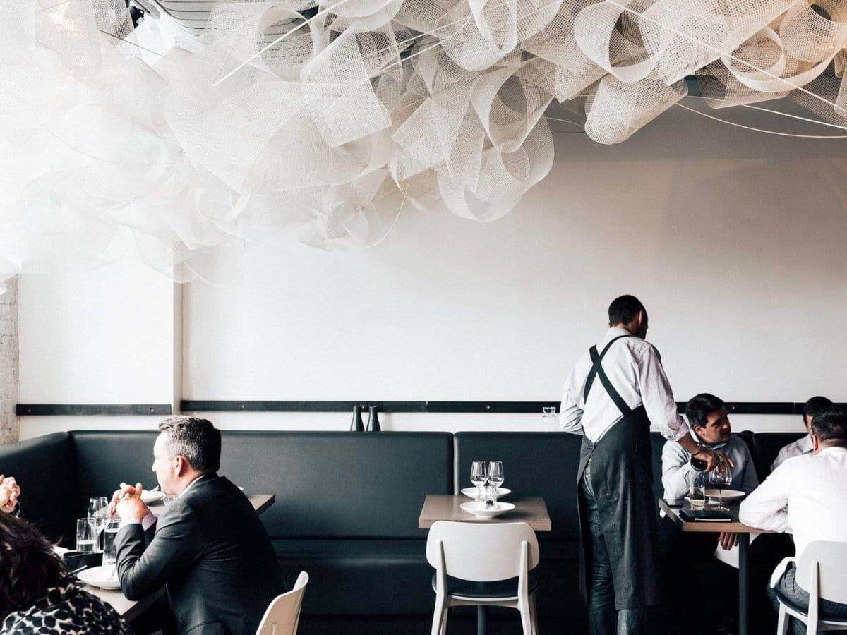 Interior of Tonka restaurant with black and white colour scheme and elaborate ceiling decor showing customers dining