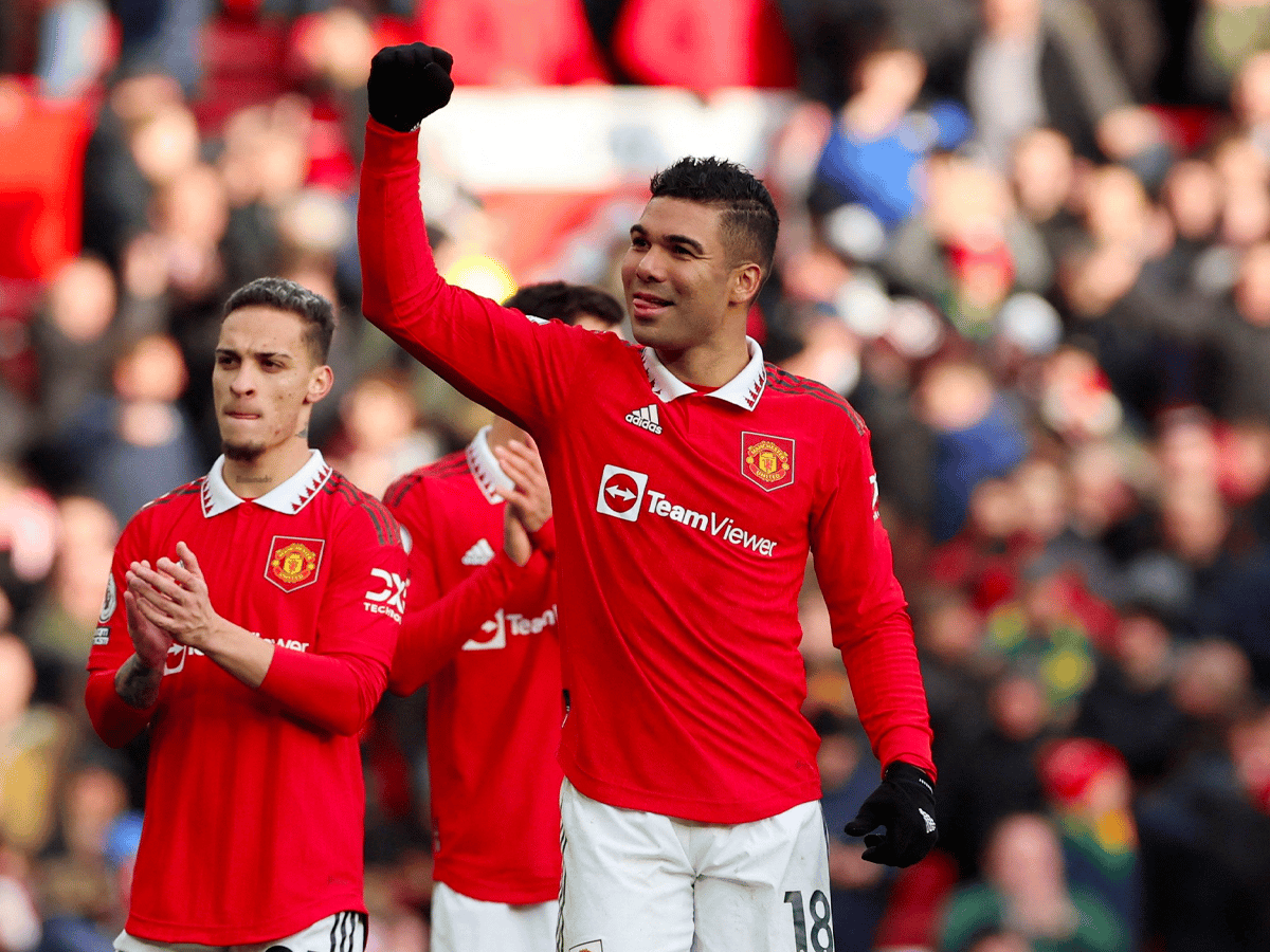 Manchester United players in red jerseys celebrating on the field, with one player raising his fist.