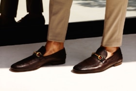 Man's legs wearing khaki pants and brown horsebit loafers