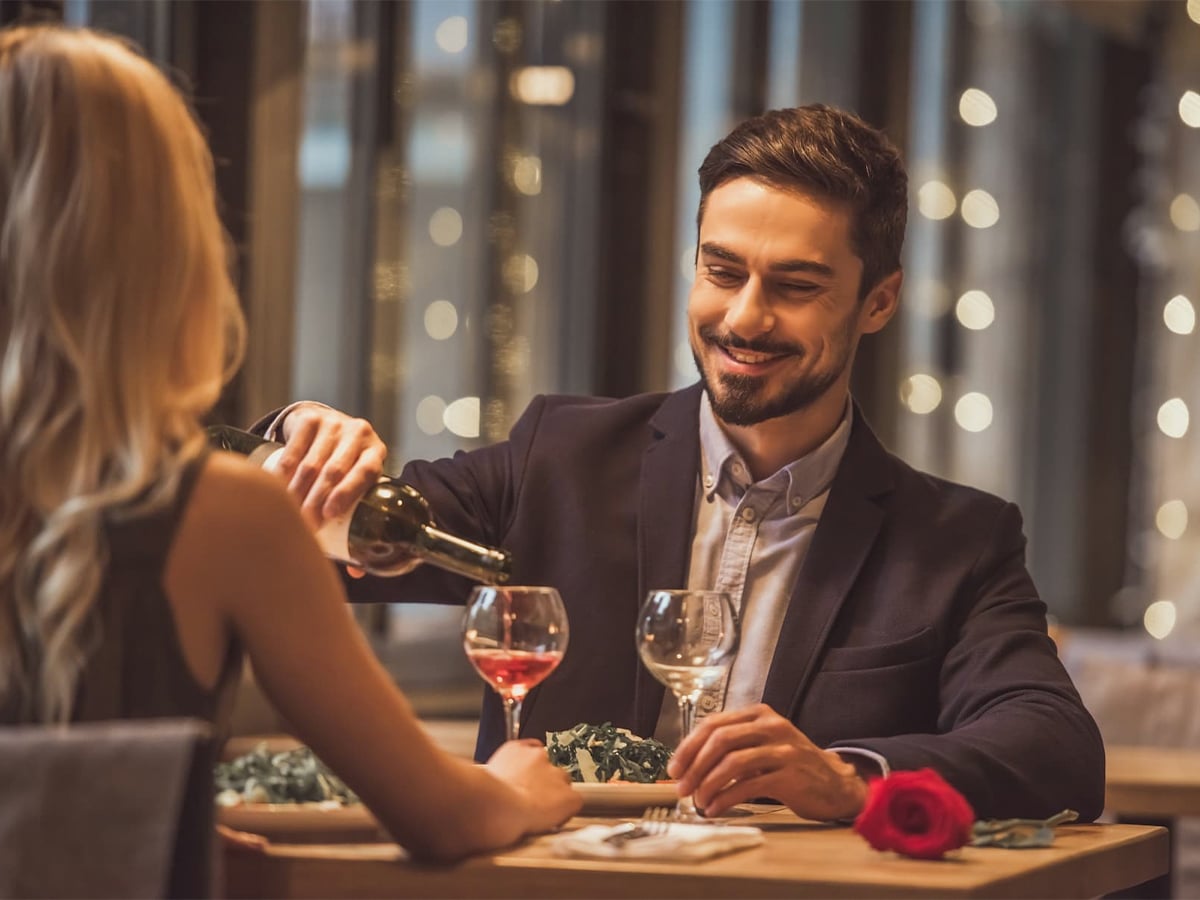 Couple dining at a fancy restaurant, man pouring wine for his date