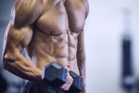 Athletic man with abs working out using dumbbells