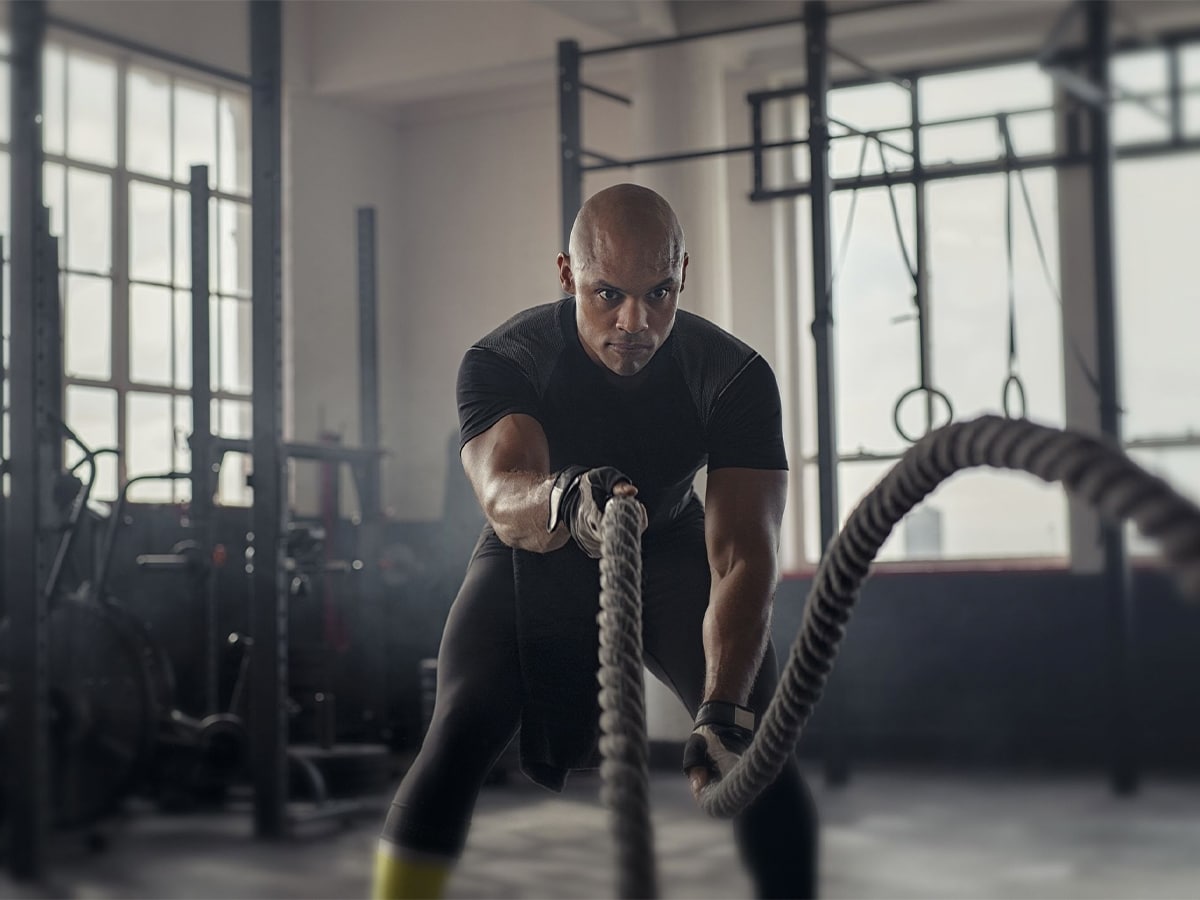 Athletic man using battle rope at gym