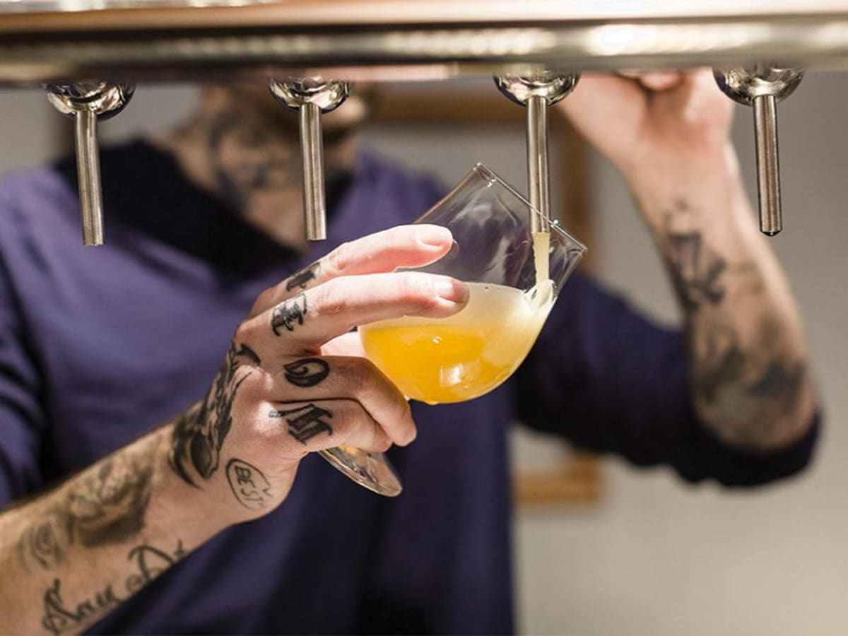 Tattooed man filling glass with beer