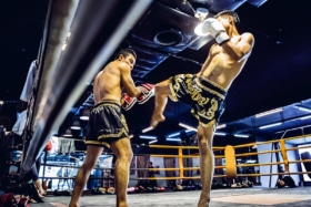 Low angle shot of two men sparring inside a muay thai ring