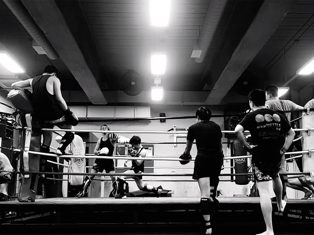 Two members sparring in the ring while other members are watching at Sydney Uni Muay Thai Club gym