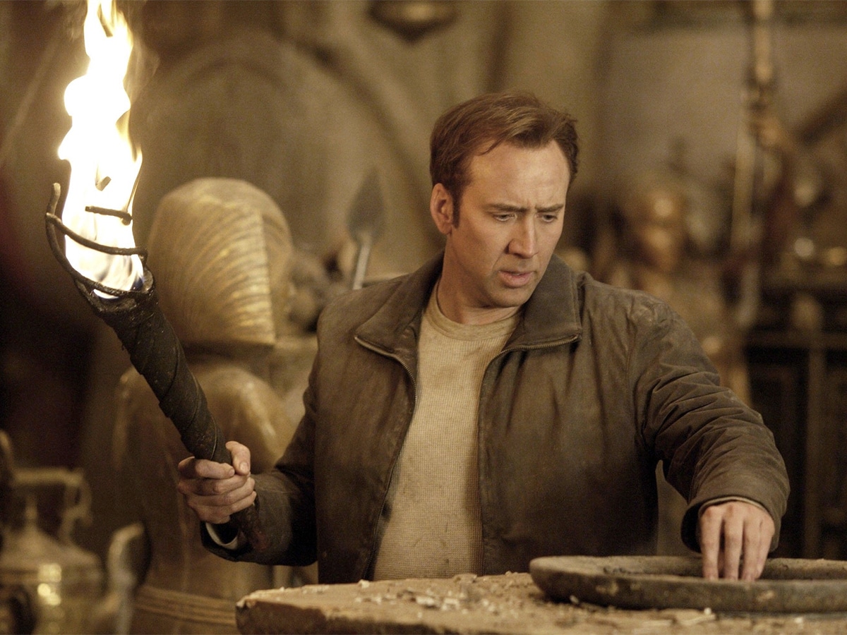 Nicolas Cage holding a torch and looking at artifacts