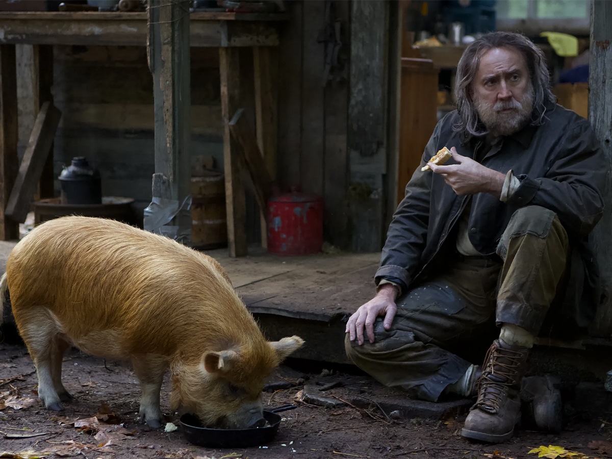 Nicolas Cage as a hermit eating with a pig
