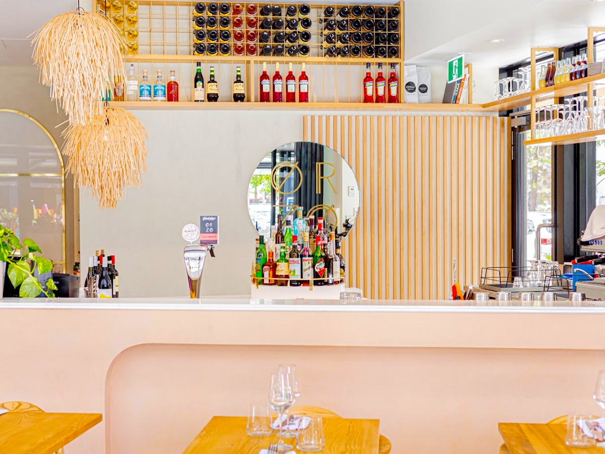 Interior of Orzo restaurant featuring a vibrant pastel colored bar with a polished counter and liquor bottle display