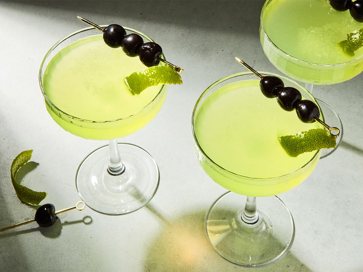 Headshot of three glasses of last word cocktail each served with three skewered maraschino cherries