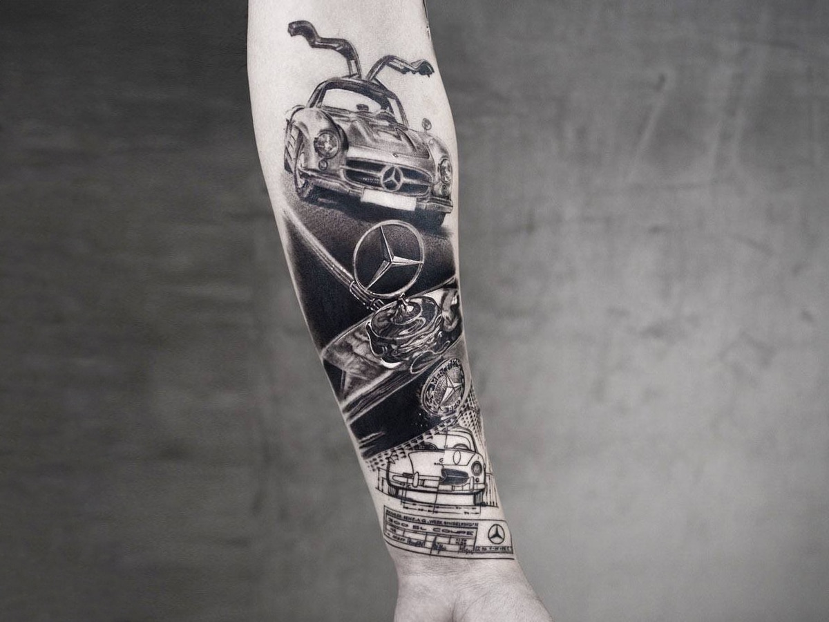 Black and gray tattoo of a stylized Mercedes-Benz car on a man's arm