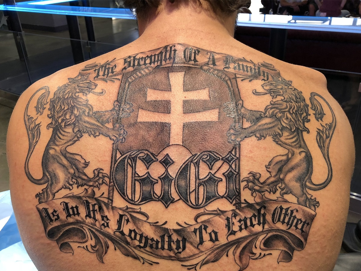 Big black and gray tattoo of a family crest covering a man's whole upper back