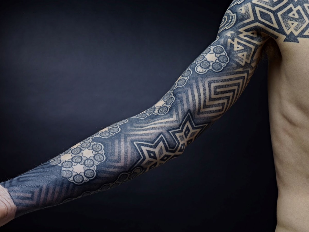 Black and gray geometric design tattoo sleeve on a man's arm