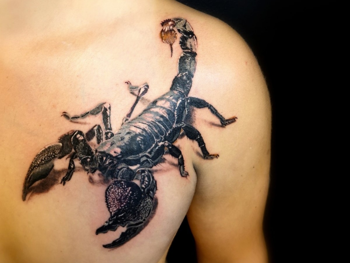 Black and gray tattoo of a scorpion on one side of a man's chest