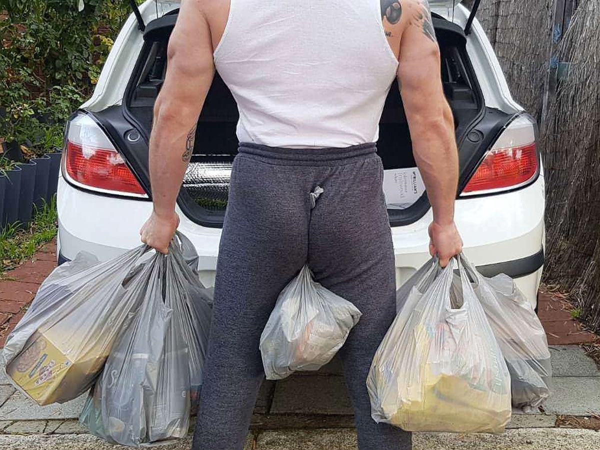 Man holding groceries with both hands and butt clench