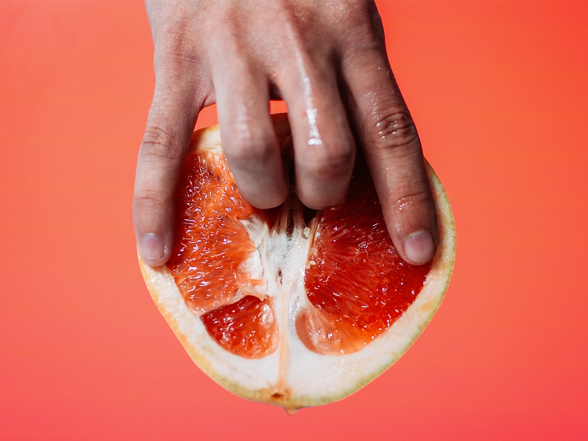 Ring and middle fingers poking the middle of a sliced pomelo
