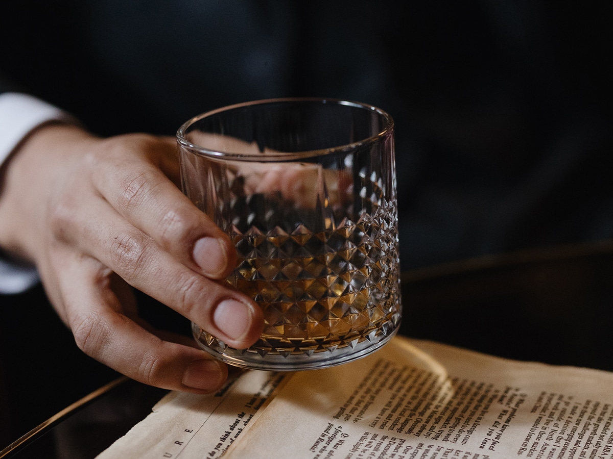 Close-up of a man’s hand holding an almost empty glass of whisky