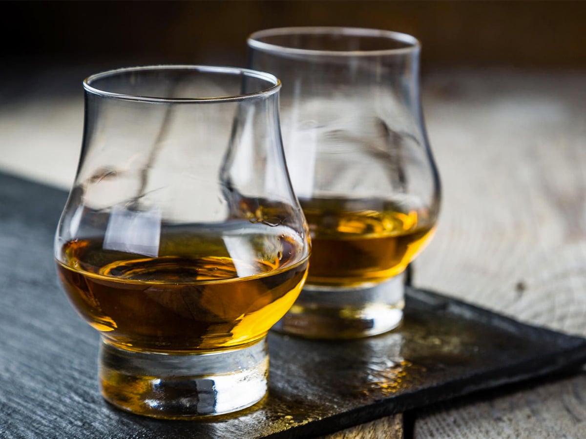 Close-up of two glasses of whisky on a rustic wood background