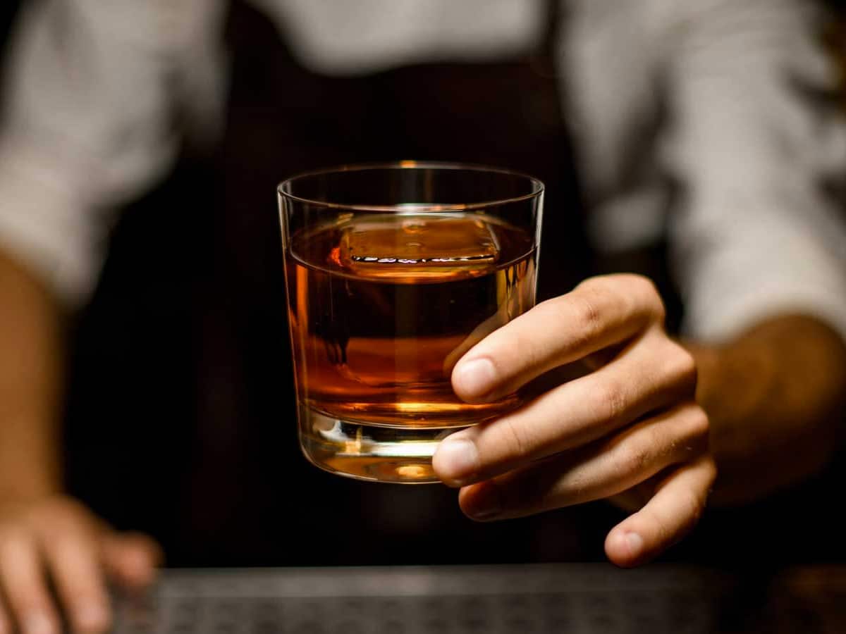 Close up of a man’s hand holding a glass of whisky
