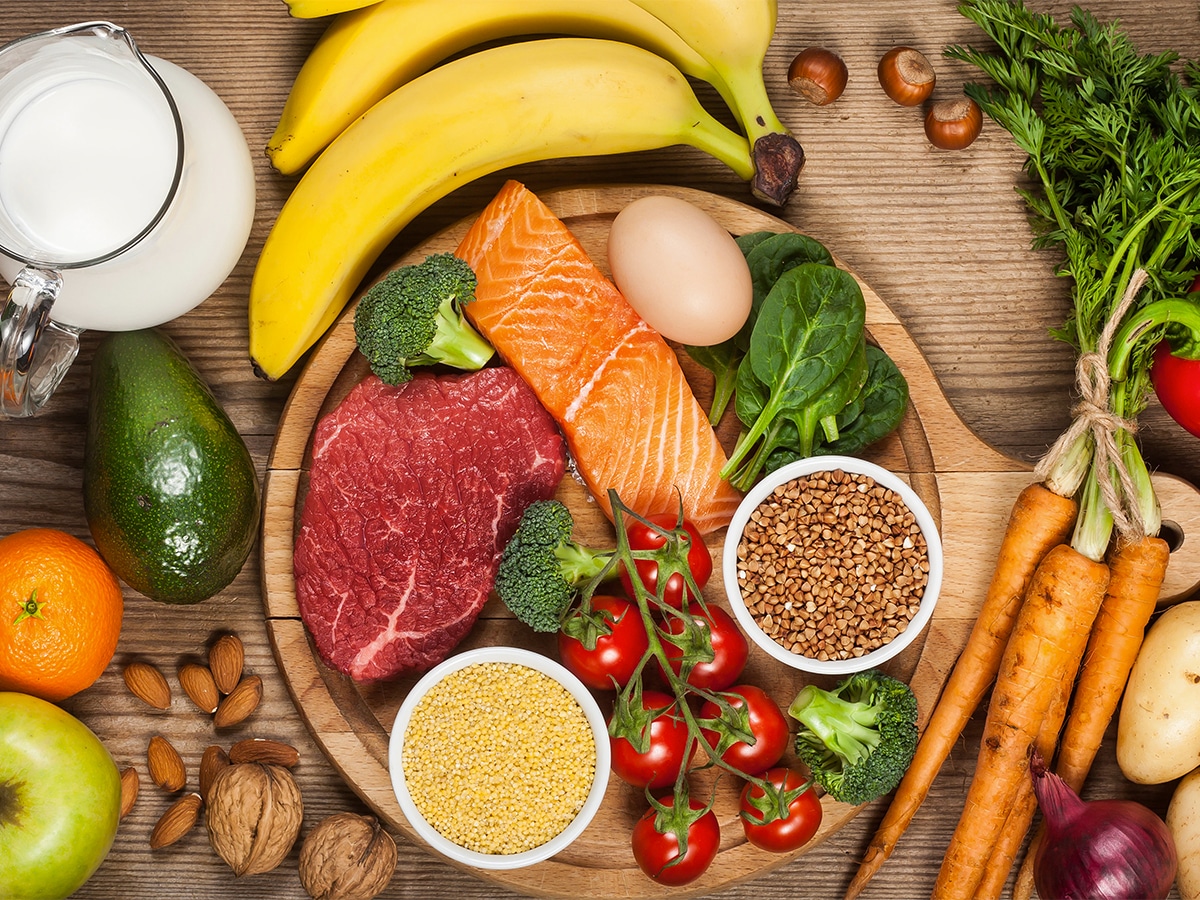 Overhead shot of vegetables, fruits, and meat on a wooden table