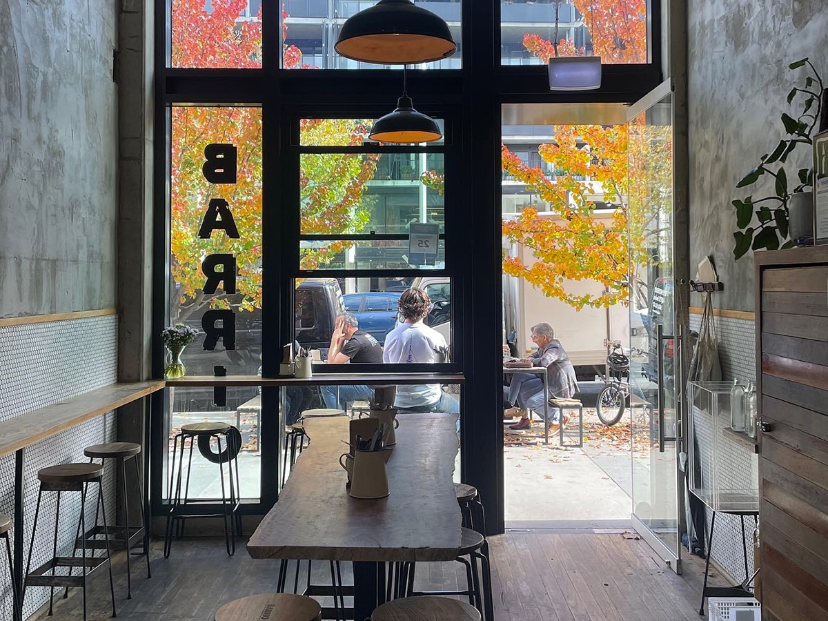 Interior of Barrio Collective Coffee cafe with wide glass windows showing customers outside