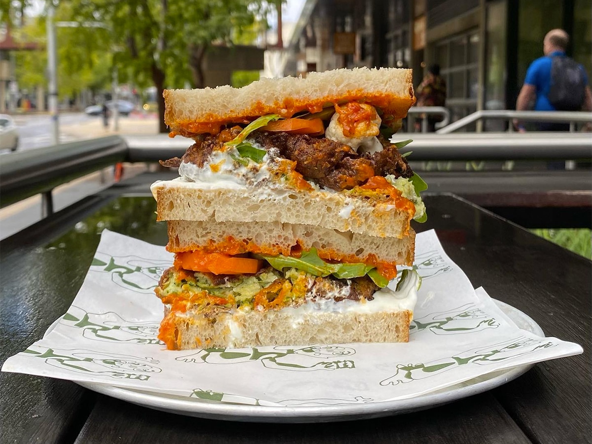 Close up shot of a sandwich on a plate with custom deli paper taken outdoor