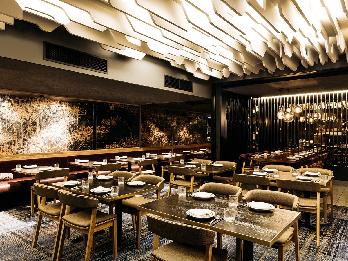 Interior of Maha restaurant with dirty white and wood colour scheme showing tables, chairs and elaborate wall decor