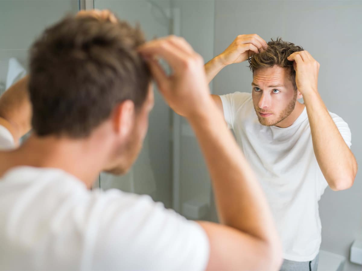 Man fixing his hair looking at his reflection in the mirror