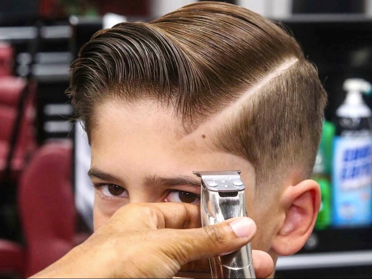 Close up of clipper near a man’s head with a side part haircut