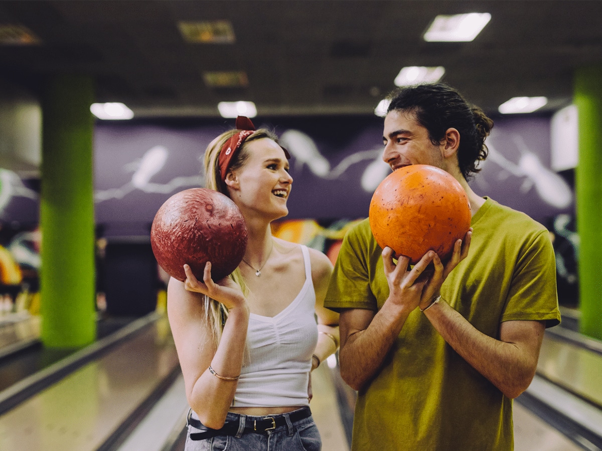 Young couple at the bowling alley with the balls looking at each other