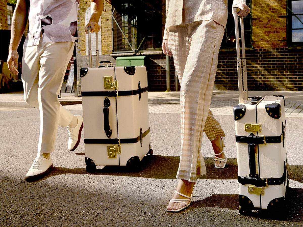 Lower half body shot of a man and a woman dragging their Globe Trotter Centenary Large Check-In suitcase outdoor