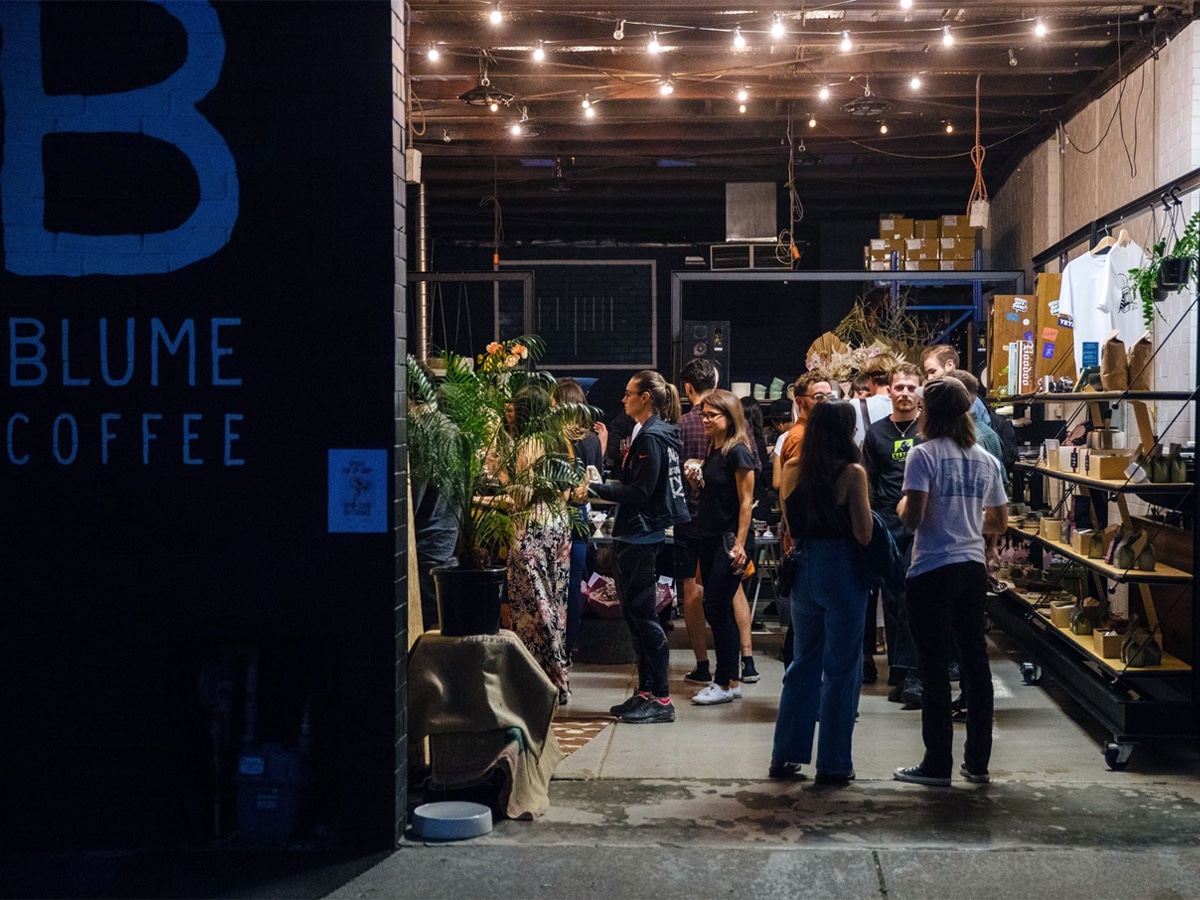 Exterior of Blume Coffee cafe at night showing customers lined up
