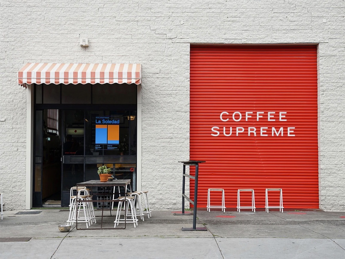 Exterior of Coffee Supreme cafe with red and white colour scheme showing tables and chairs outside