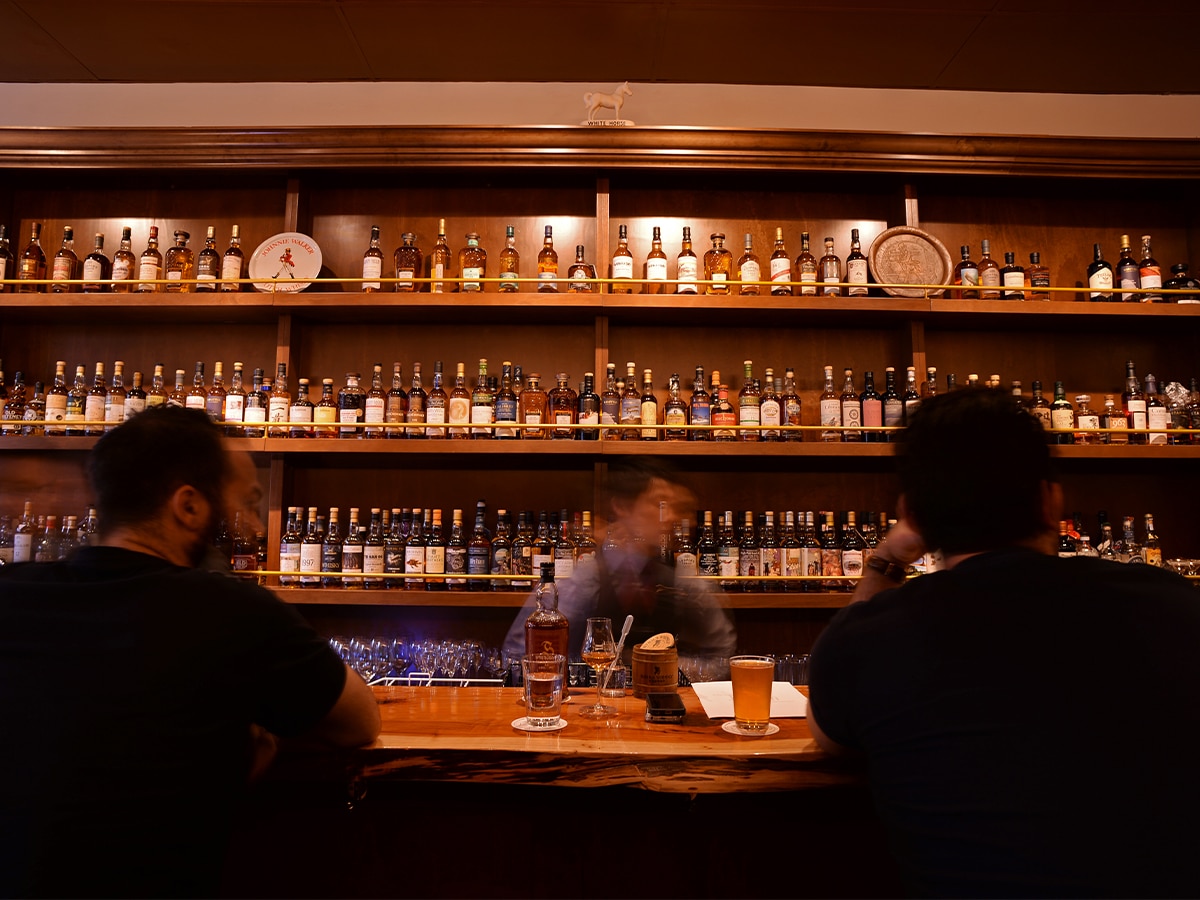 Interior of The Elysian Whisky Bar with staff behind bar area and two customers