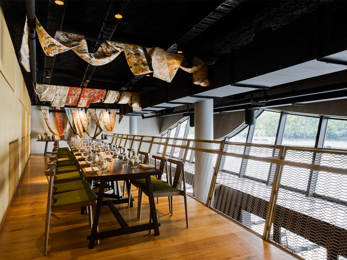 Interior of Saké Restaurant and Bar with long table, chairs and traditional Japanese fabric ceiling decor