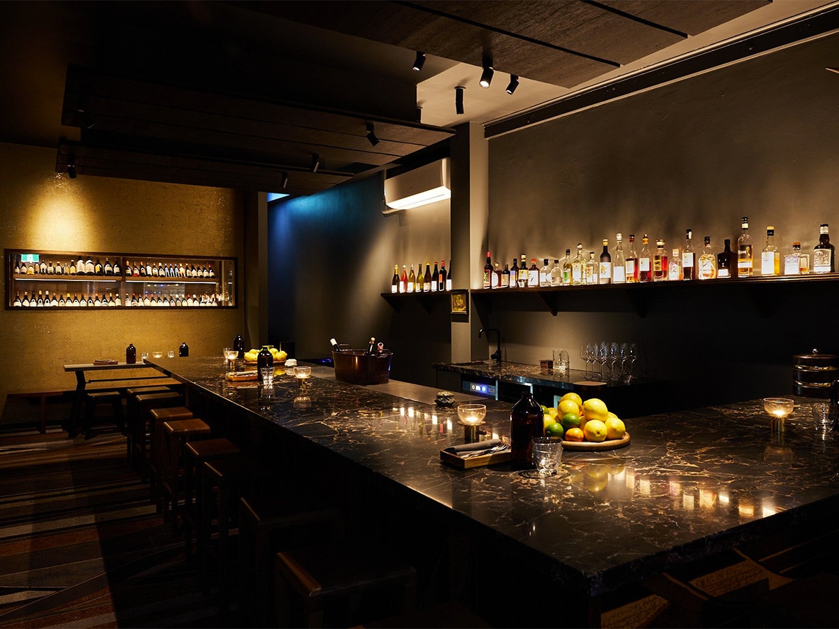 Interior of Ides restaurant with dim lighting, bar, and liquor display