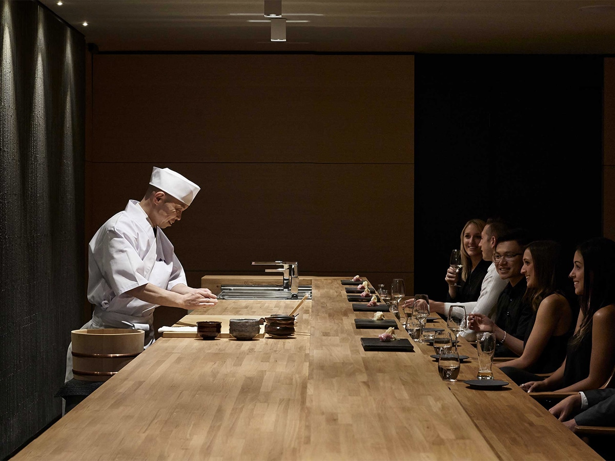 Interior of Minamishima restaurant with sushi master preparing food behind the bar with customers watching on the other side