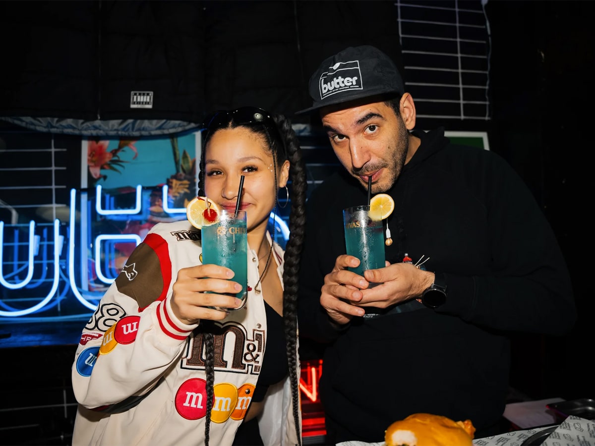 Man and woman holding drinks looking at camera