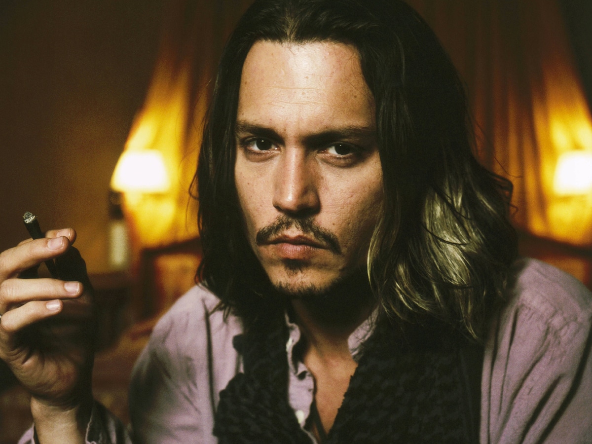 Johnny Depp with with long hair holding a cigarette