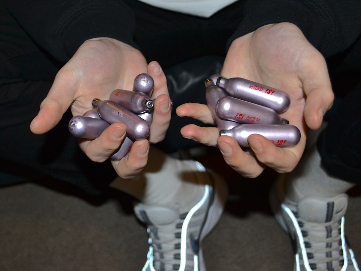 Pair of hands holding nangs canisters
